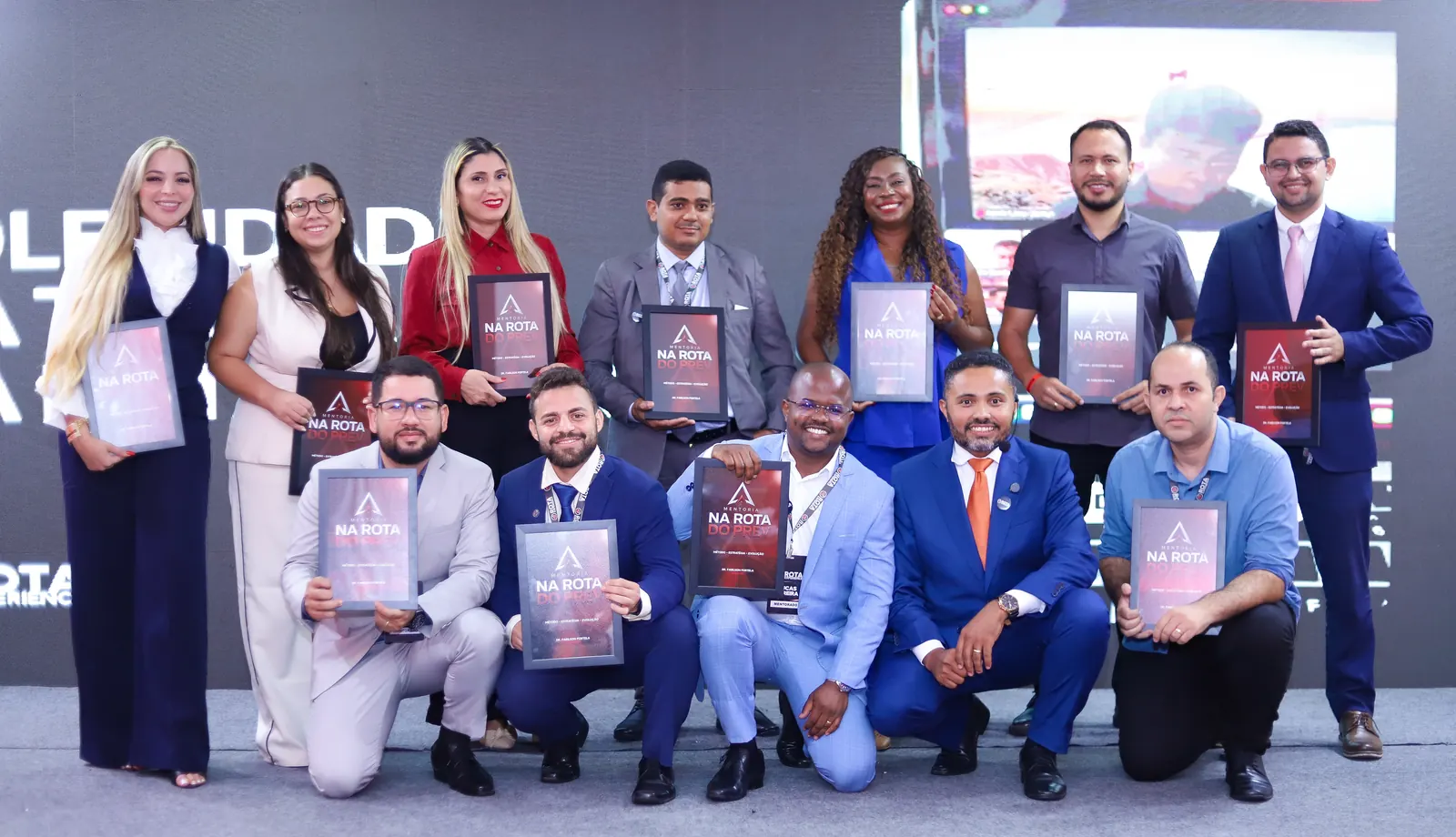 Turma de alunos reunida no palco com os certificados da mentoria